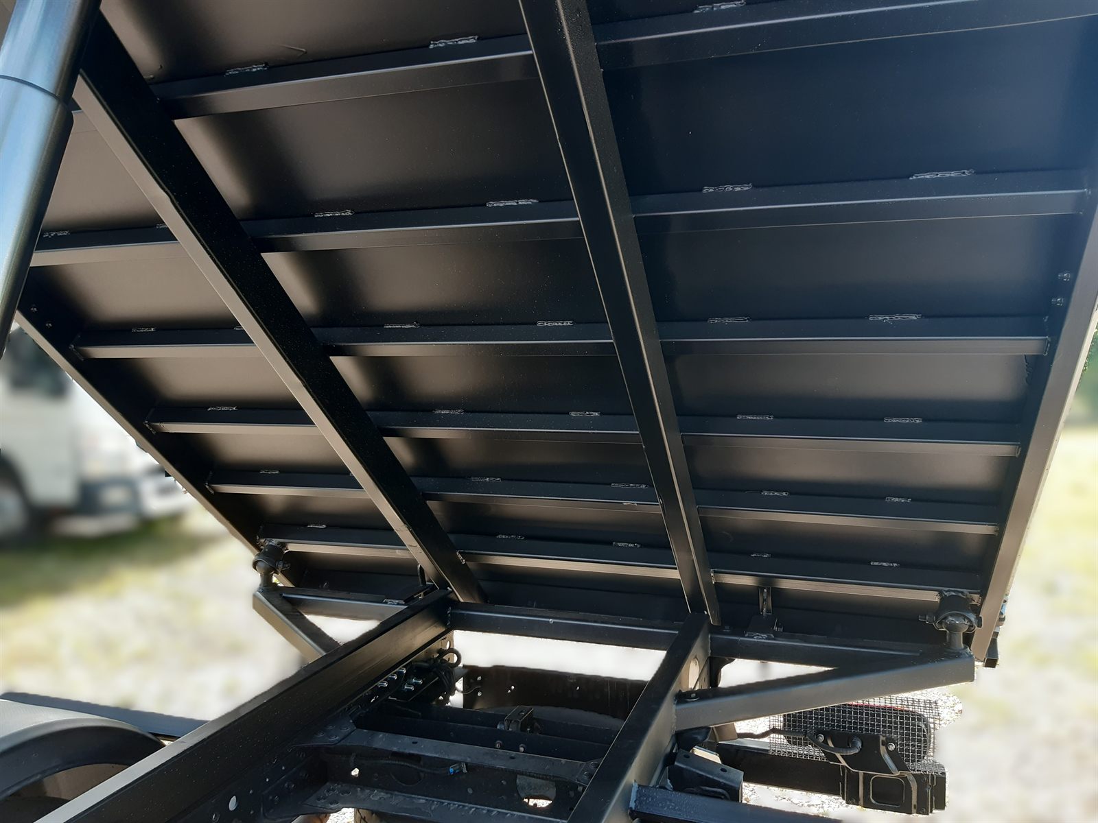 Underside of a raised tipper — steel profile frame and steel sheet floor